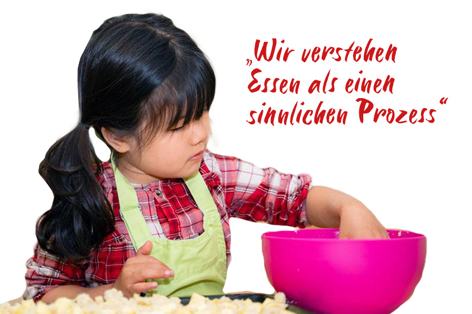 Ein junges Mädchen bereitet mit Freude Essen in einer Schüssel einen Kuchenteig zu. Ein Schriftzug heißt: Wir verstehen Essen als einen sinnlichen Prozess.